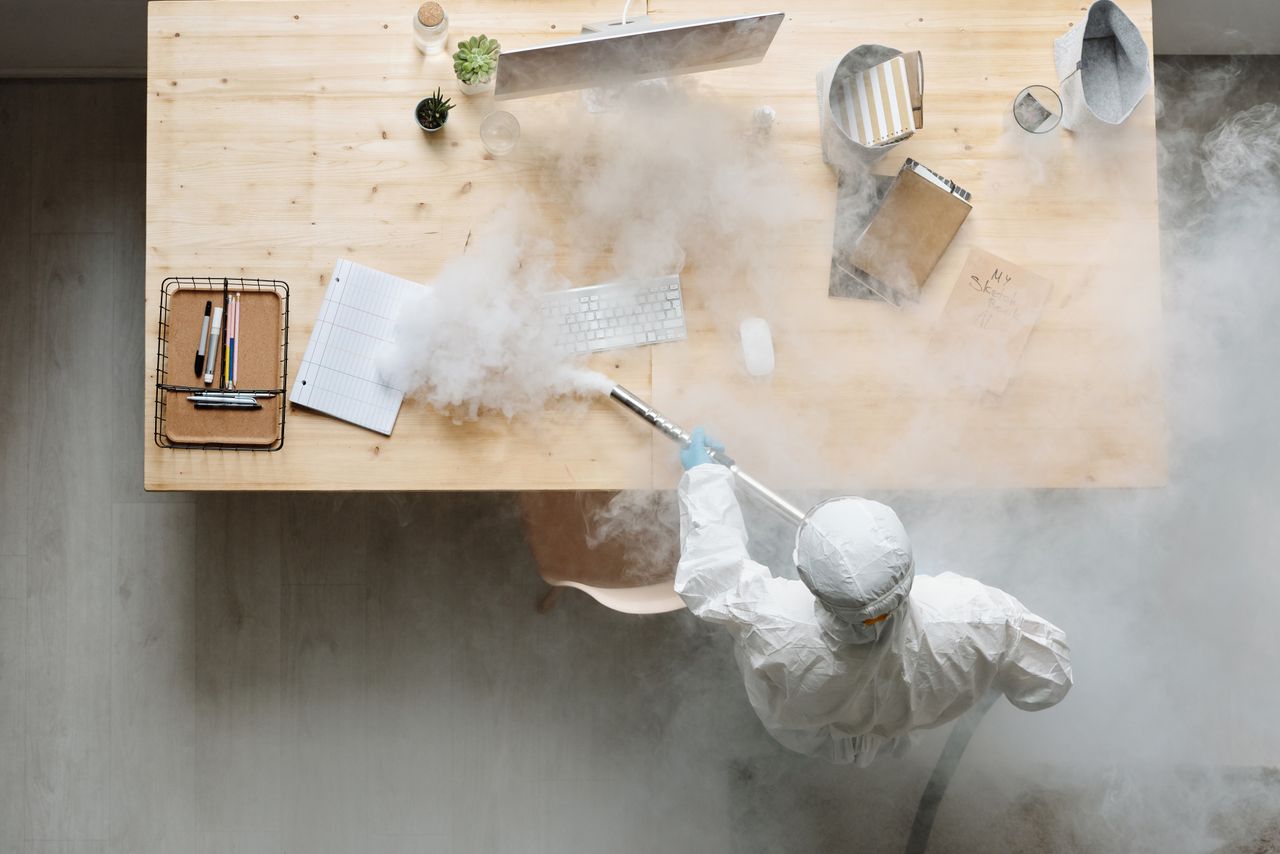 expertise-01 An individual disinfects a workspace using fumigation, wearing full protective gear for safety.